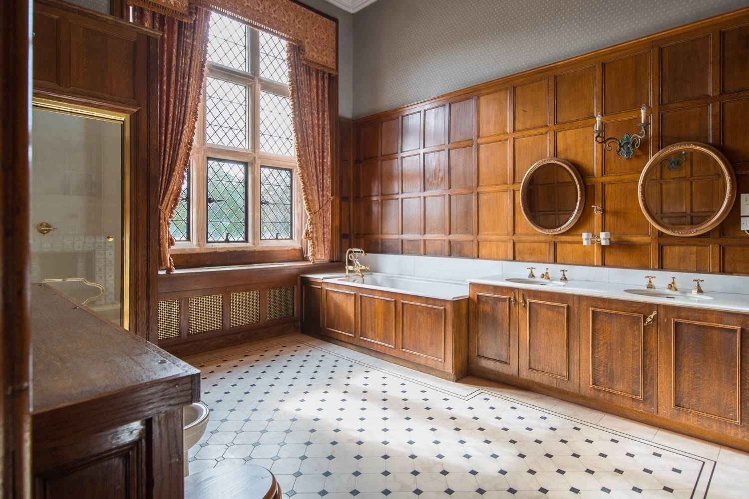 Period master bathroom shoot space featuring full wood-panelled walls, built-in bathtub surround, and tiled flooring by Love Locations.