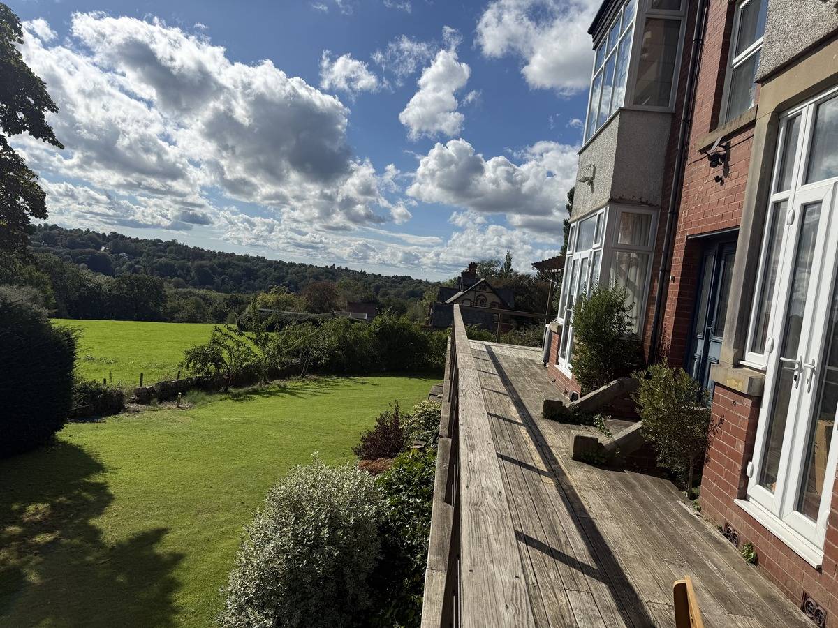 High-level view from an elevated balcony deck looking across scenic green country fields in Stockport SK6 by Love Locations.