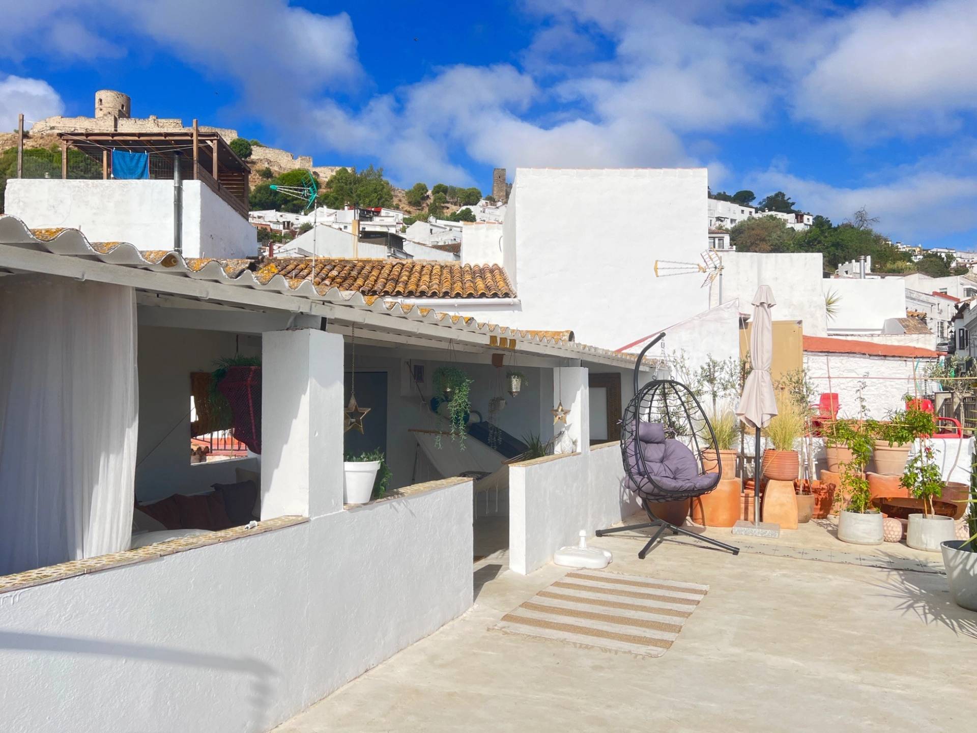 Covered outdoor rooftop lounge shoot location in Jimena de la Frontera Cádiz through Love Locations, featuring white rendered archways, wicker hanging chairs, and open country views.