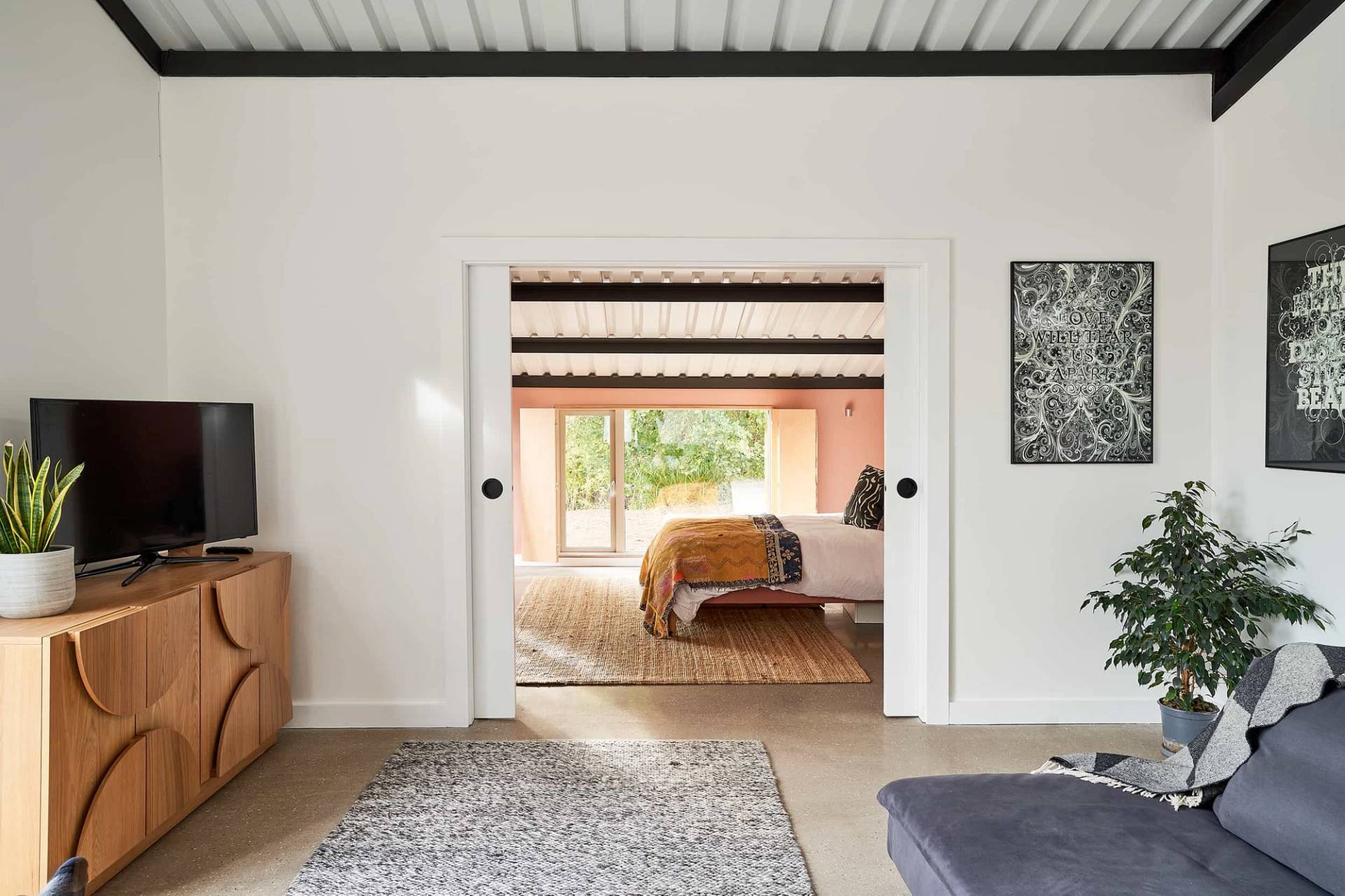 View looking through double doors down a polished concrete corridor connecting guest bedroom suites, Love Locations IP30.