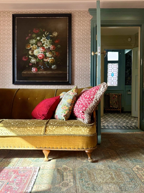 Gold velvet settee with red throw pillows in a period living room with patterned wallpaper, Love Locations N13.