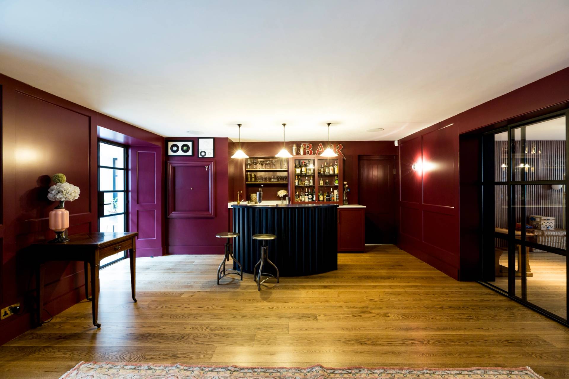 Moody dark red speakeasy bar room in Camberwell, SE5 with fluted dark blue bar counter and wooden floors via Love Locations.