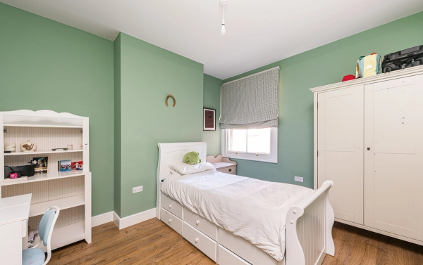 Charming kids' or guest bedroom filming location with soft sage green walls, white furniture, and wood flooring, Love Locations.