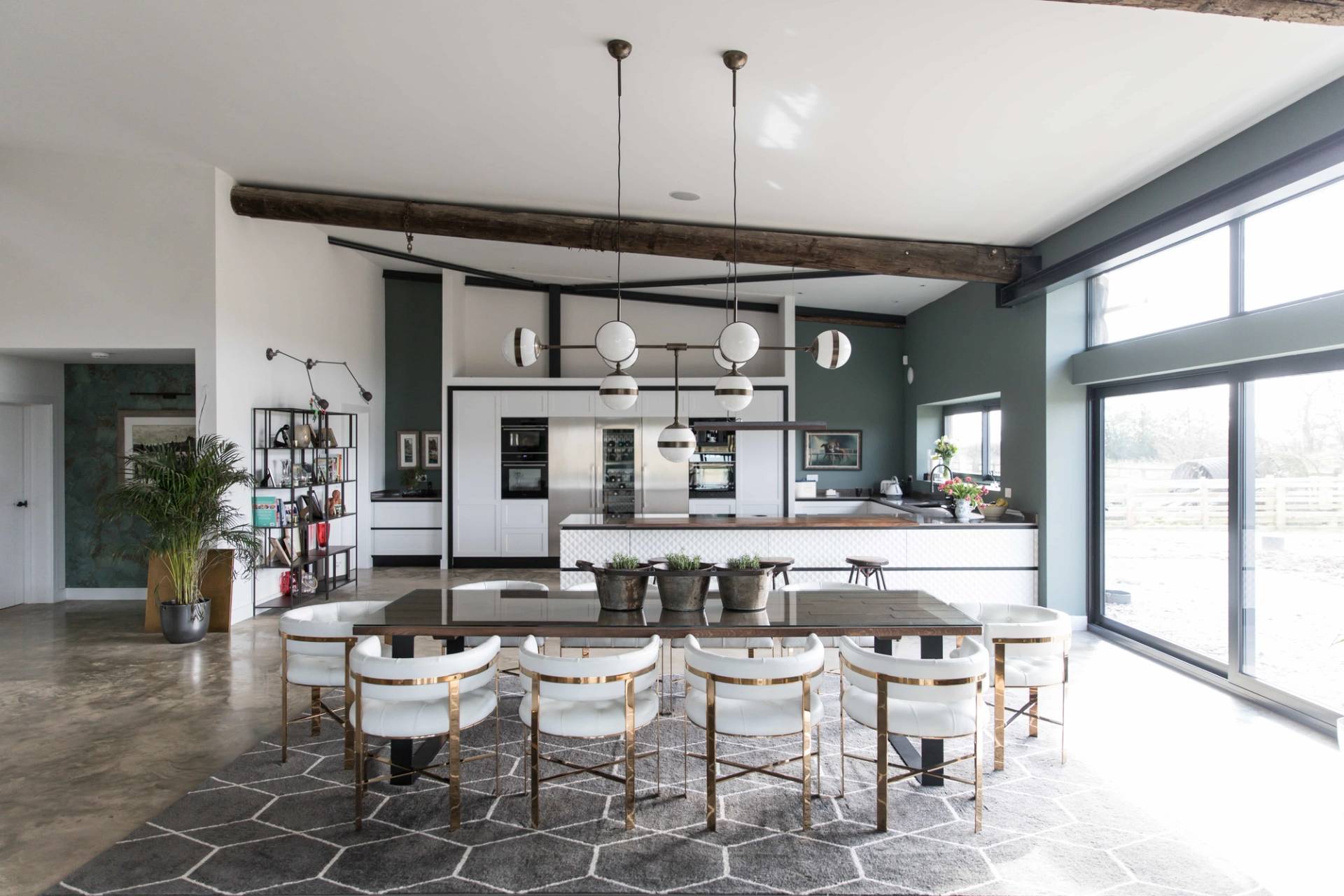 Spacious kitchen and dining area in a modern barn conversion with long dining table, hexagonal area rug, and industrial ceiling beams, Love Locations CV23.