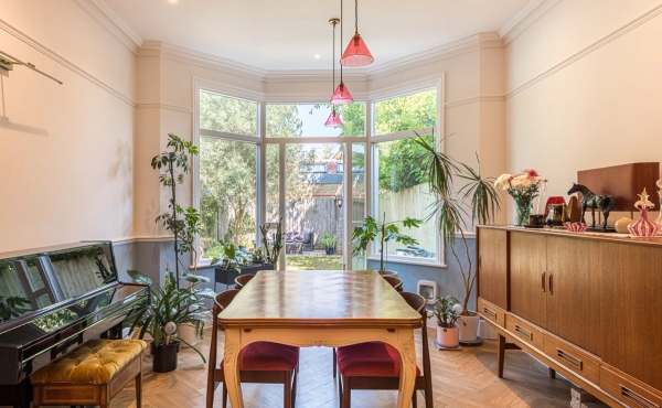 Light-filled family dining room set featuring a retro wooden table and vintage red dining chairs, bookable through Love Locations.