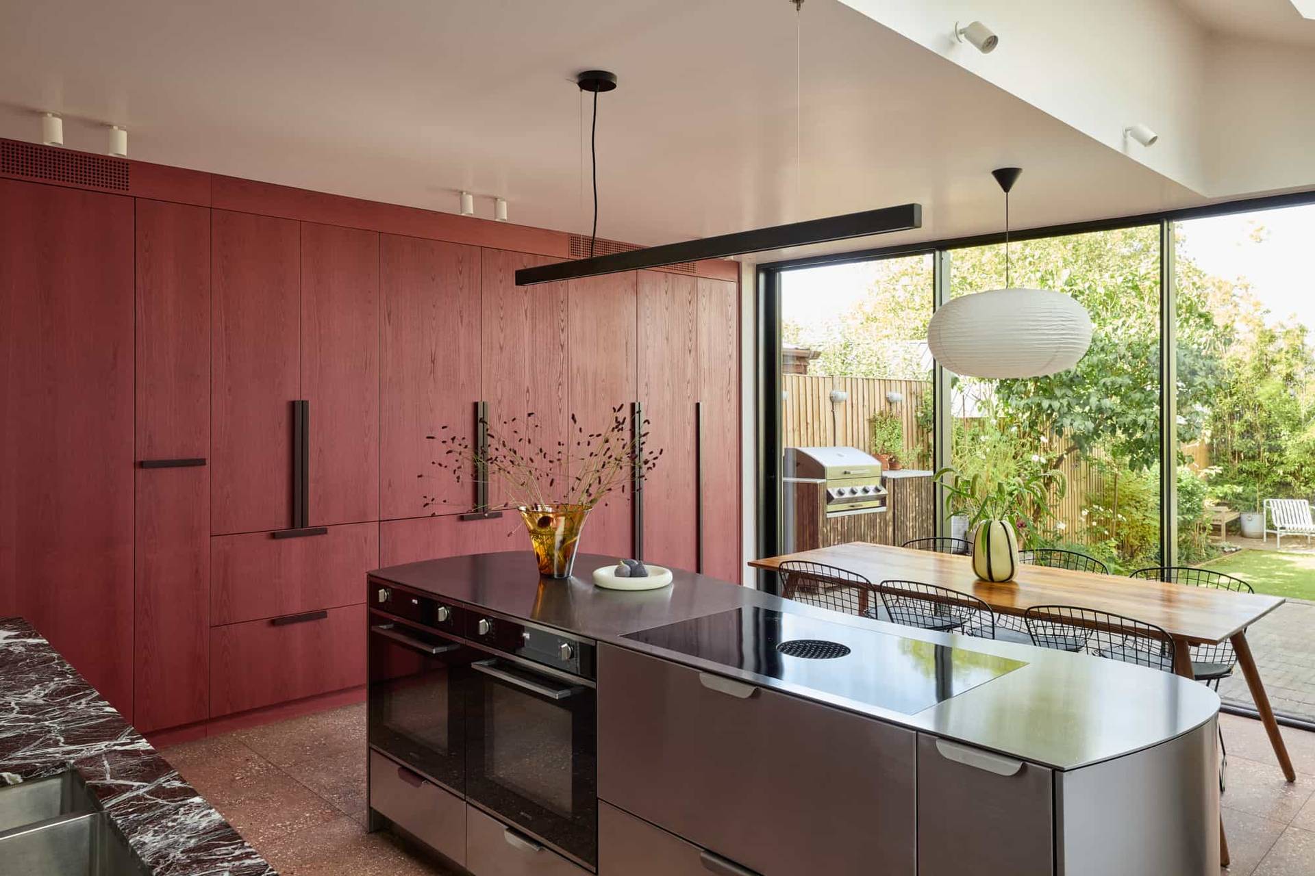 Love Locations bright open plan house SE23: Large kitchen space transitioning into a dining area with expansive glass panels facing the garden, optimized for tracking shots and drama filming.
