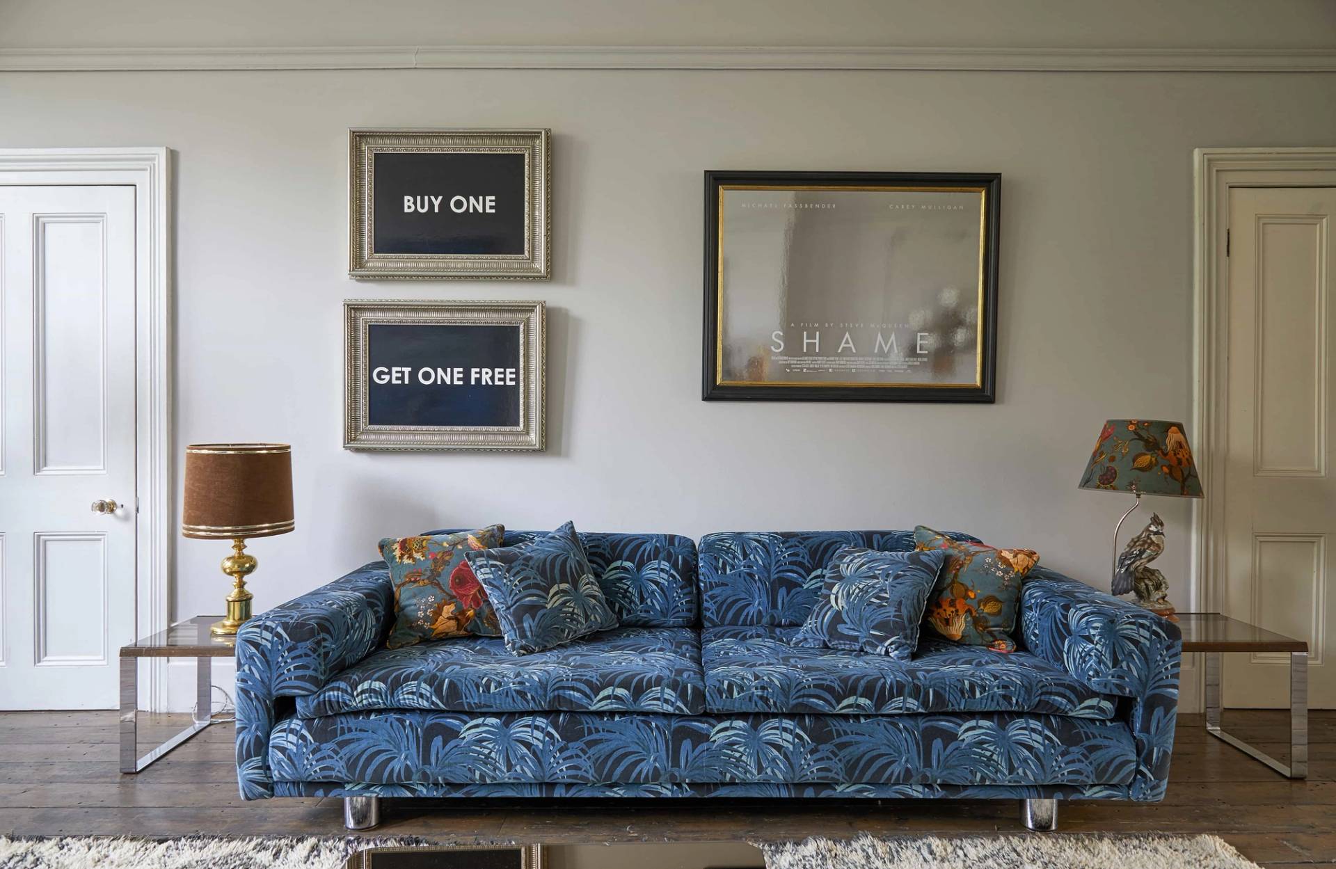 Long blue patterned sofa on geometric rug set against grey walls and vintage mirrors, Love Locations N16.