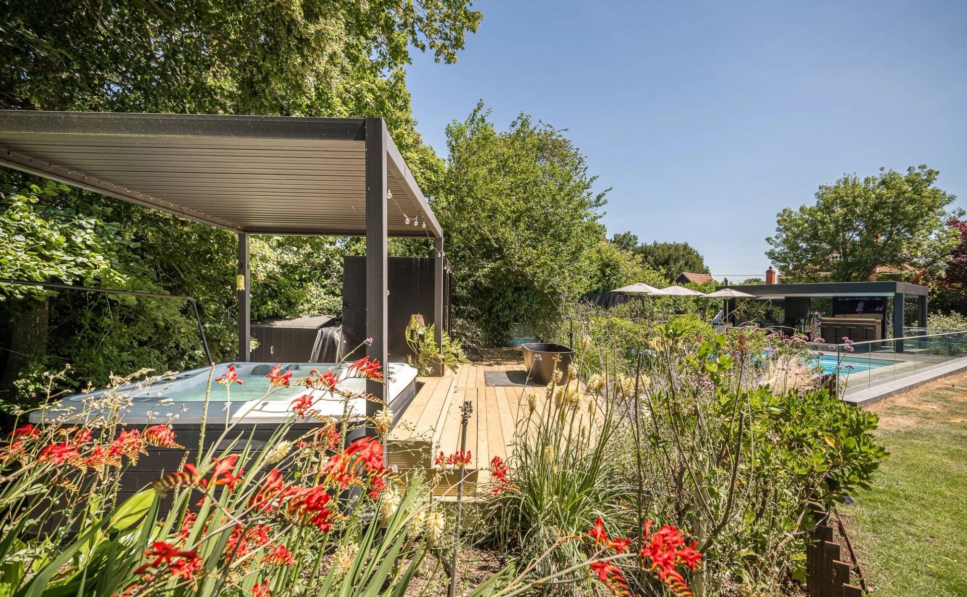 Premium outdoor hot tub jacuzzi sunken into timber decking surrounded by manicured landscaping, Love Locations CM3.
