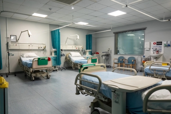 Patient ward room featuring adjustable medical beds, bedside tables, and privacy curtains, Love Locations UB4.