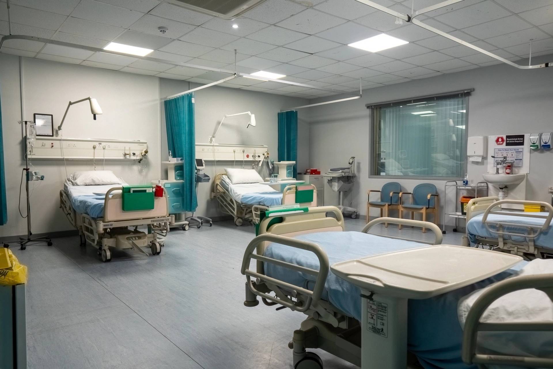 Patient ward room featuring adjustable medical beds, bedside tables, and privacy curtains, Love Locations UB4.