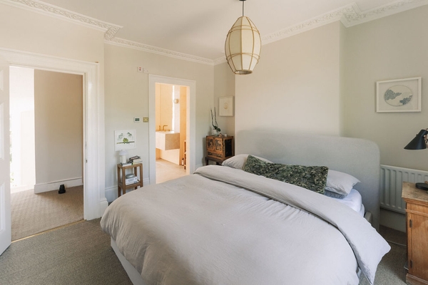 Serene bedroom view looking through an open doorway toward a luxury wood-panelled ensuite bathroom, Love Locations SW9.