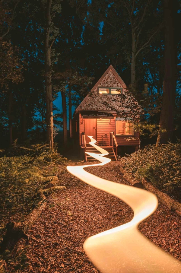 Stunning night photography set showing a glowing wooden cabin with a beautifully lit winding walkway trail cutting through the dark woods, Love Locations.