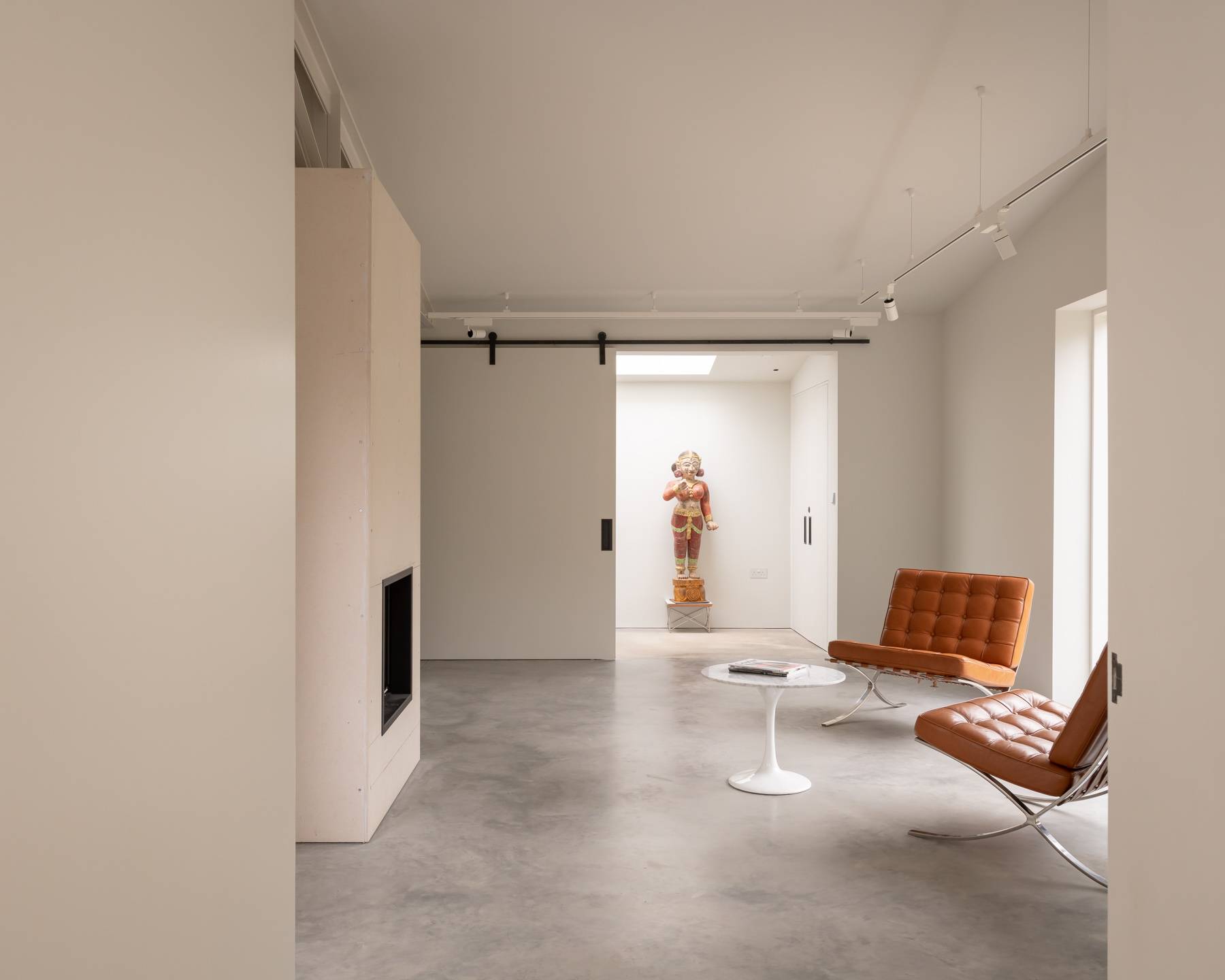 Minimalist reception room with modern hearth fireplace, cognac leather chairs, and gallery doorway, Love Locations BN3.
