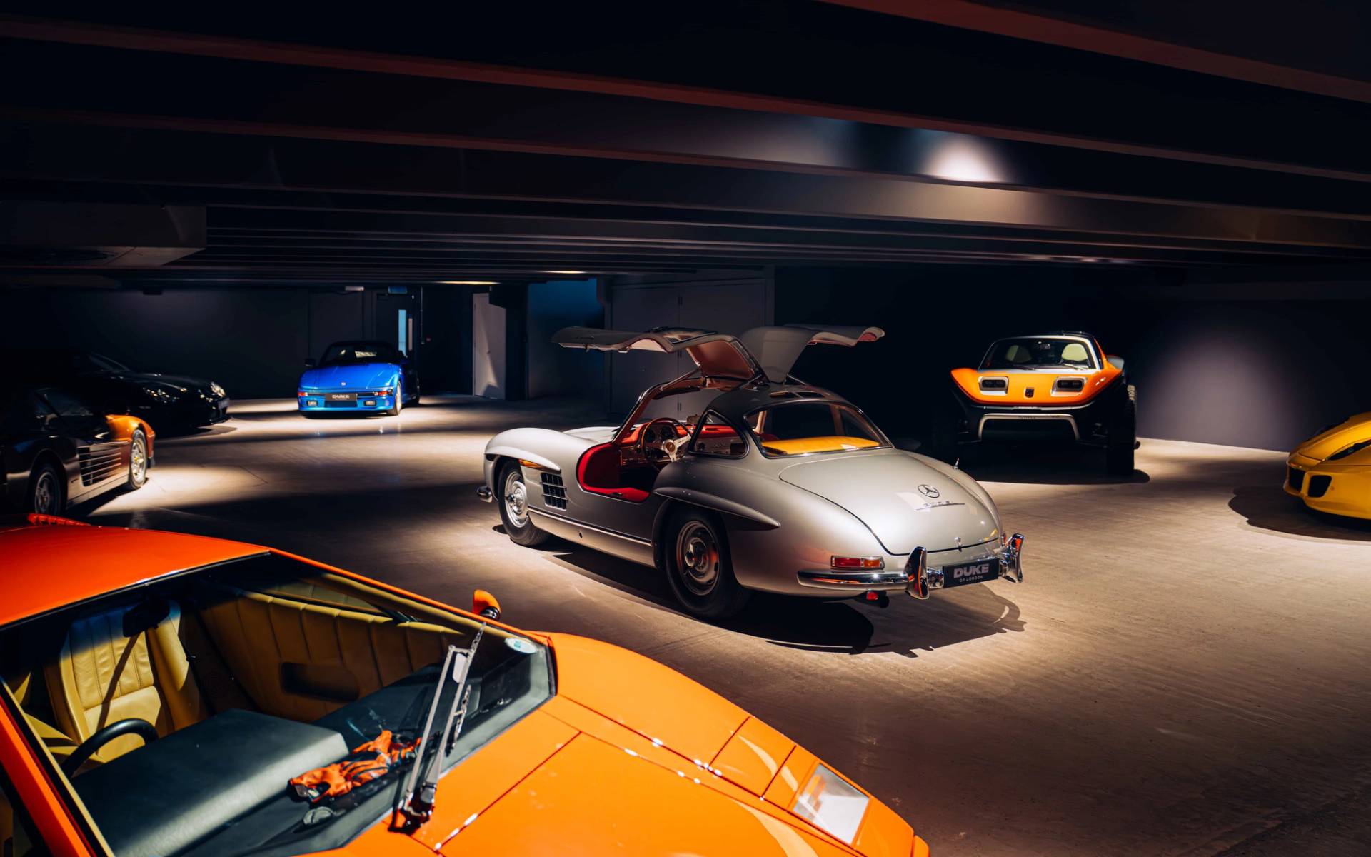 Classic silver sports car with gullwing doors illuminated inside a dark underground shoot space by Love Locations.