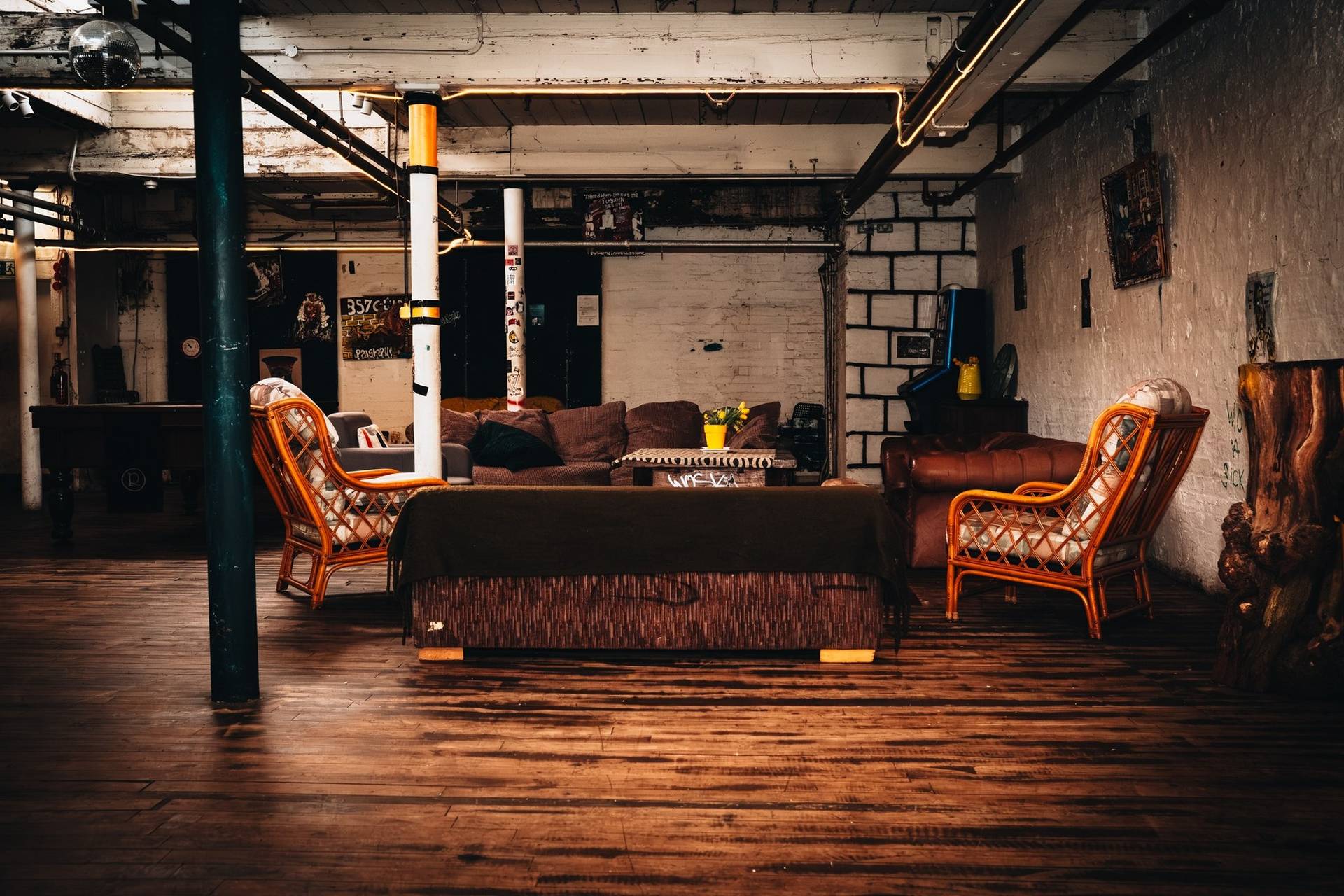 Vintage lounge and green room area featuring leather sofas, rattan armchairs, and wooden floors in Cheetham Hill through Love Locations.