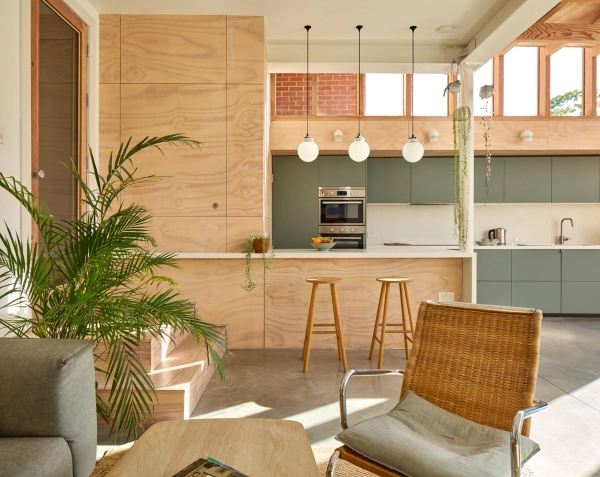 Sunlit kitchen island breakfast bar with wooden stools and plywood wall lining in Walthamstow, Love Locations E17.
