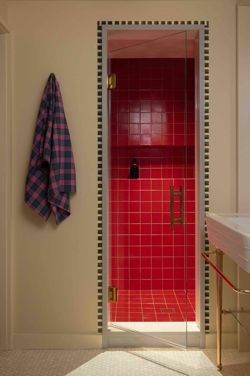 Intimate red-tiled shower stall detail in a 19th-century Brooklyn townhouse shoot venue curated by Love Locations, featuring a plaid towel accent.