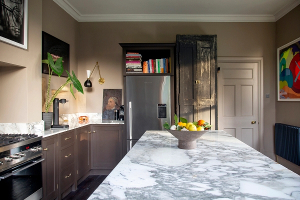 Marble kitchen island counter set with a fruit bowl and dark wood storage cabinets, Love Locations ME13.