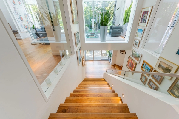 High-angle architectural view looking down a modern wooden floating staircase with glass balustrades, ideal for premium carpet or flooring lookbooks, Love Locations W4.