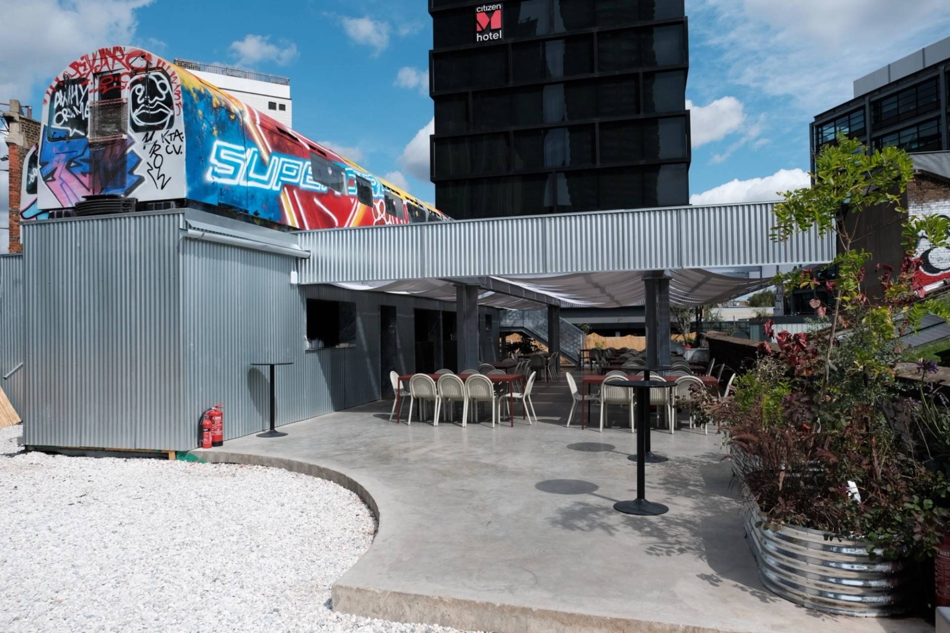 Outdoor rooftop terrace and event space in Hackney EC2A from Love Locations, with paved patio areas, outdoor dining chairs, and urban views.