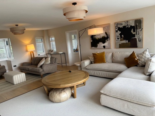 Bright contemporary lounge film location in Essex CM4 via Love Locations, showcasing light neutral decor, wooden flooring, stylish wall art, and an arc floor lamp.
