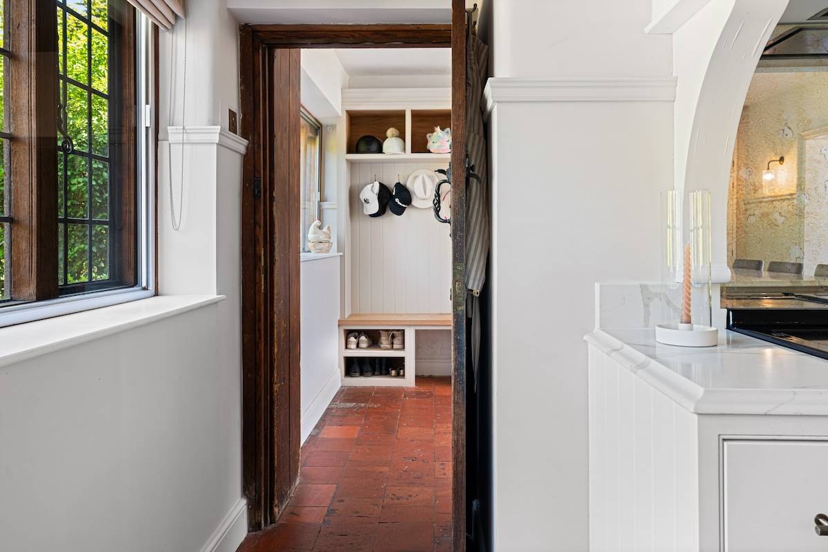 Doorway transition from a white hallway into a terracotta tiled boot room, Love Locations RH13.