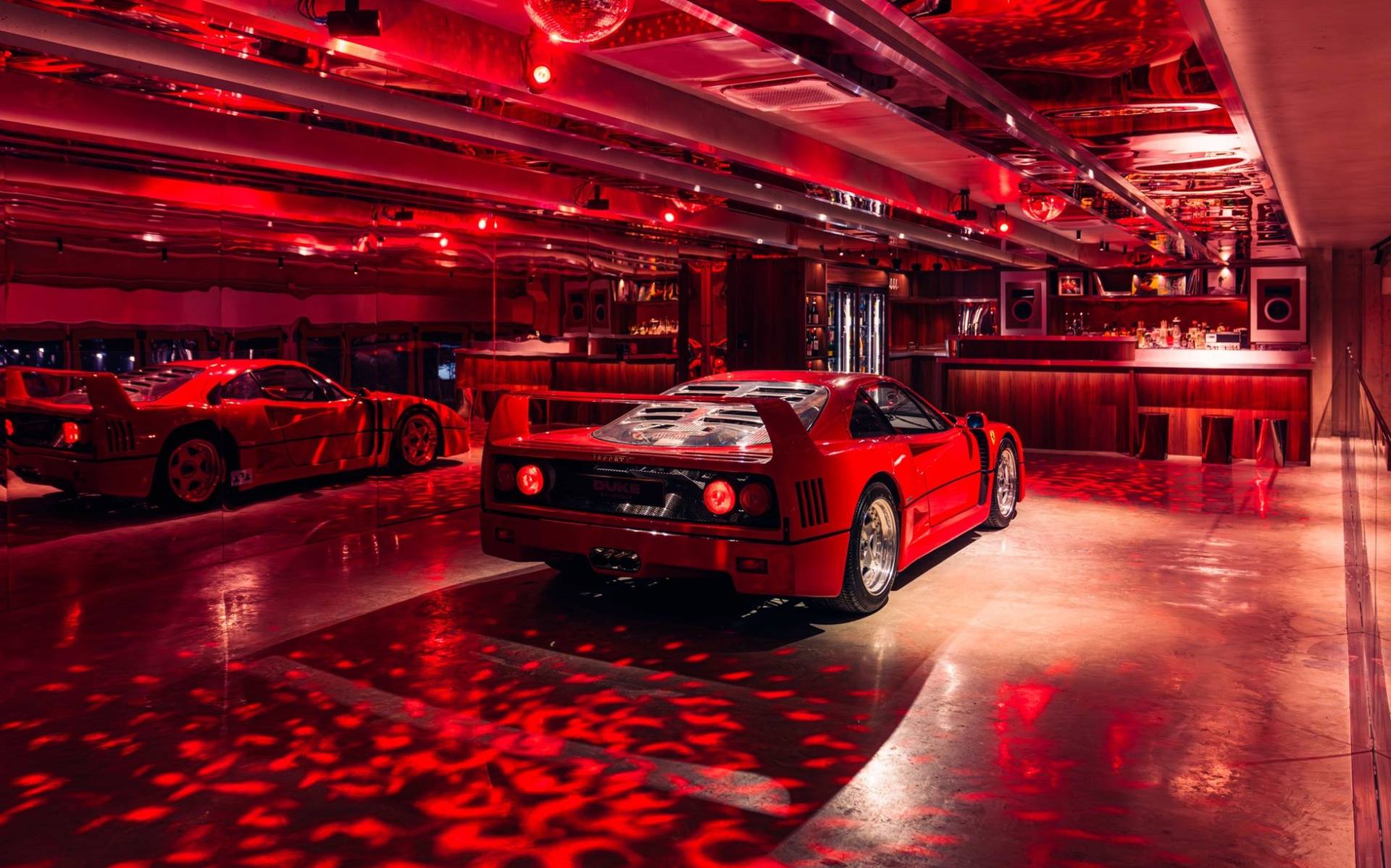 Rear view of a red Ferrari F40 in a dark red-lit nightclub or venue shoot space in Brentford TW8 by Love Locations.