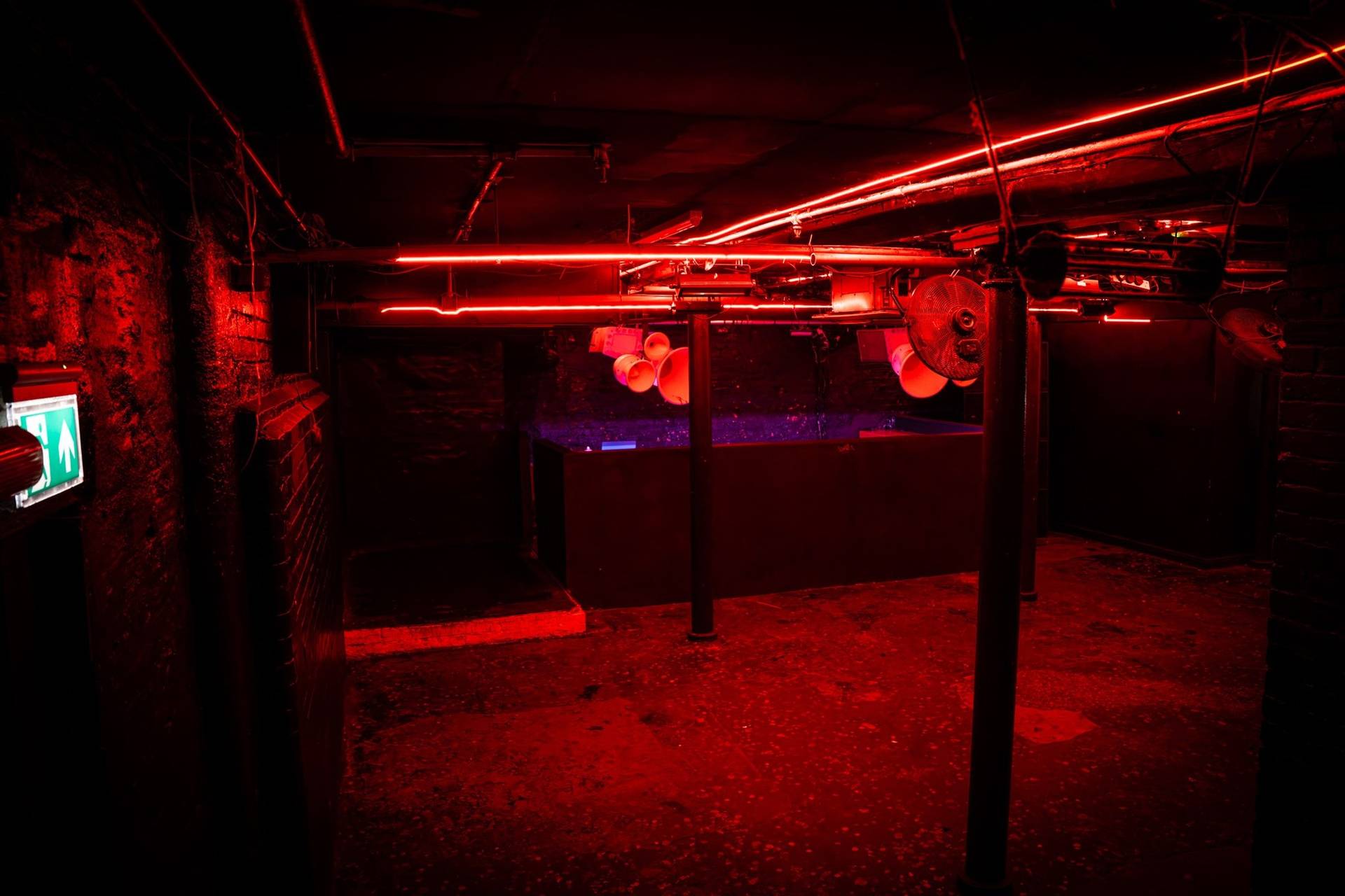 Underground dance floor and DJ station bathed in intense red lighting in a Cheetham Hill shoot venue through Love Locations.