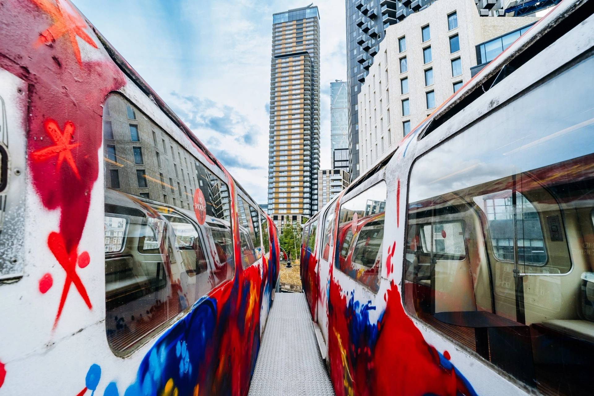 Exterior view between two colorful graffiti-art repurposed train carriages on a rooftop in East London via Love Locations.