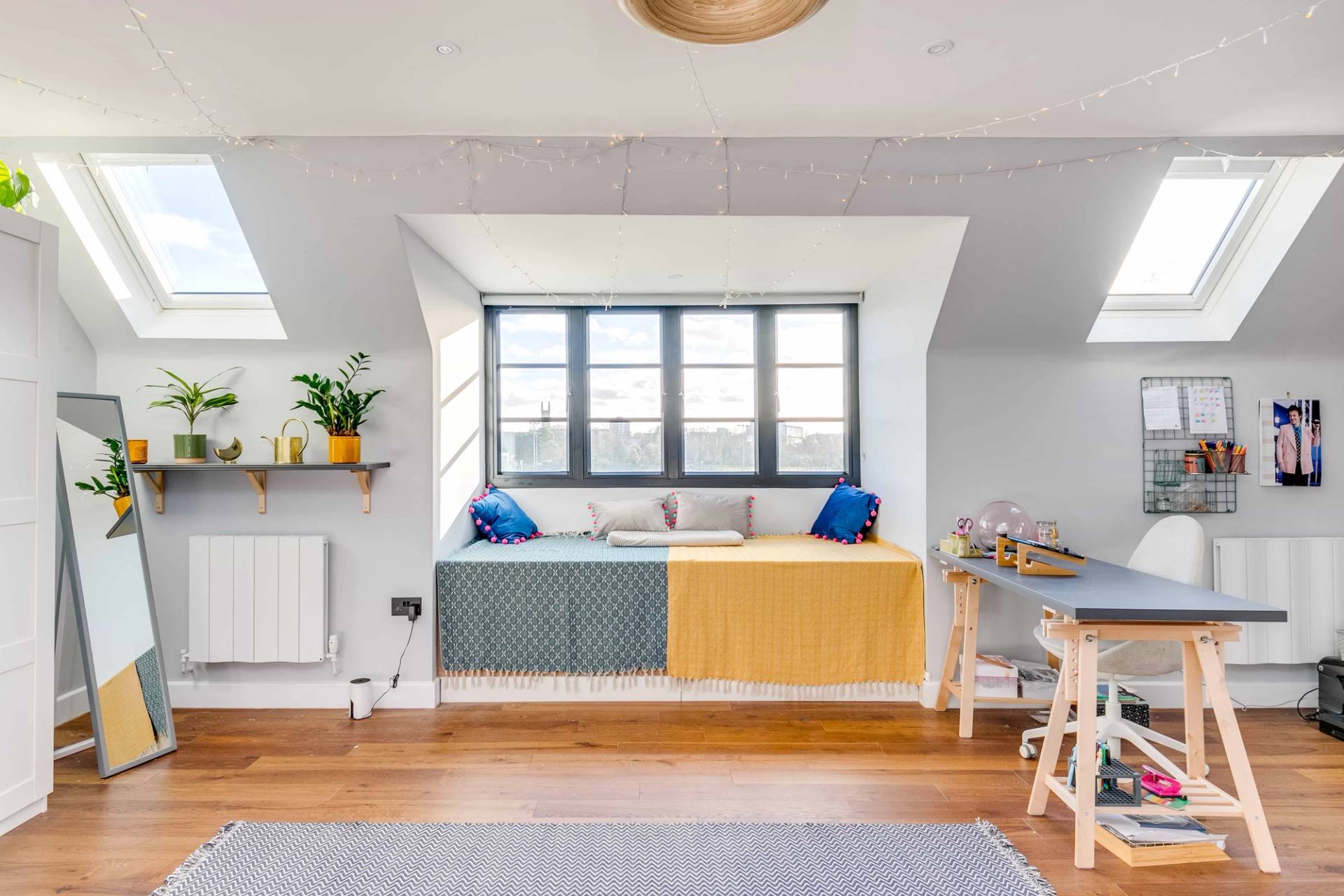 Attic window nook featuring a yellow padded window seat and writing desk setup, Love Locations CB2.