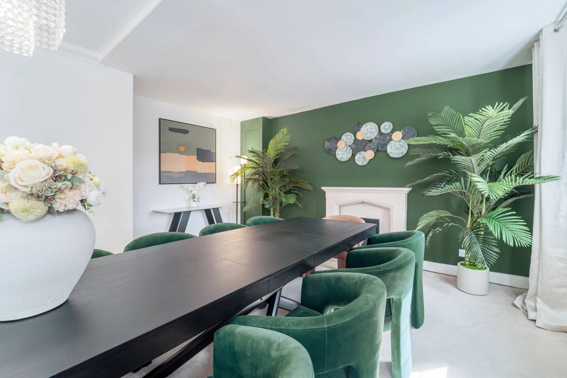 Formal dining space set with forest green velvet chairs, white fireplace, and decorative palm plants, Love Locations RM11.