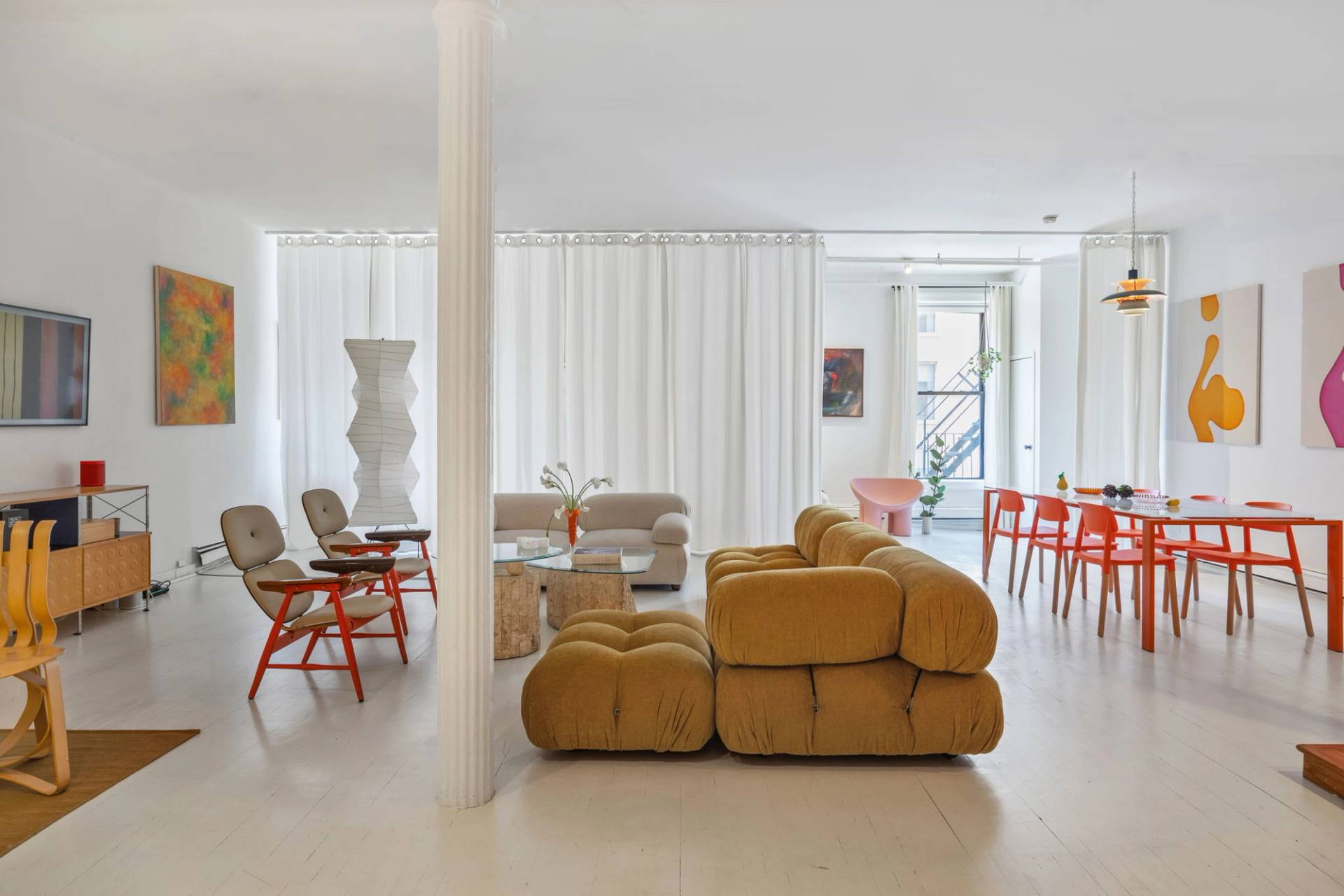 Wide open-plan living room shoot space in a white Tribeca NY 10007 loft via Love Locations, showcasing mustard yellow sectional seating, tall white columns, and sheer linen window drapes.