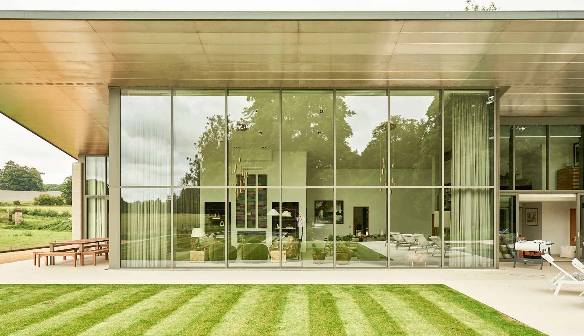Modern glass house architectural facade set behind manicured green lawns in Winchester, Love Locations SO21.
