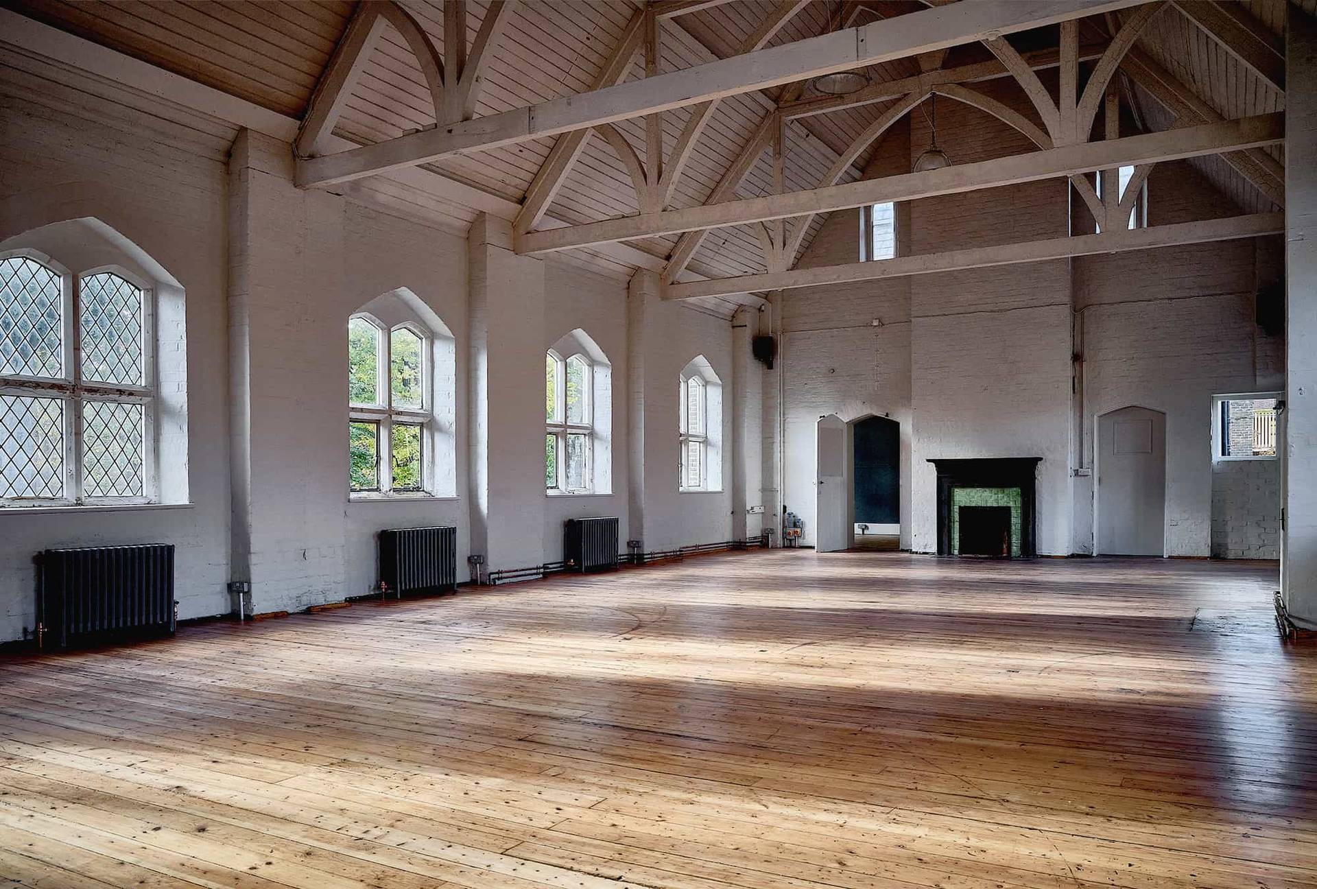 Spacious white hall room featuring arched windows and dark floorboards in an East London venue, Love Locations E2.