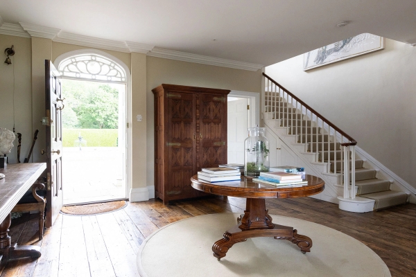 Love Locations grand entrance hall shoot location Steyning Ashington BN44: Stately reception foyer featuring a vintage mahogany round table, original wood floors, and a sweeping white staircase.