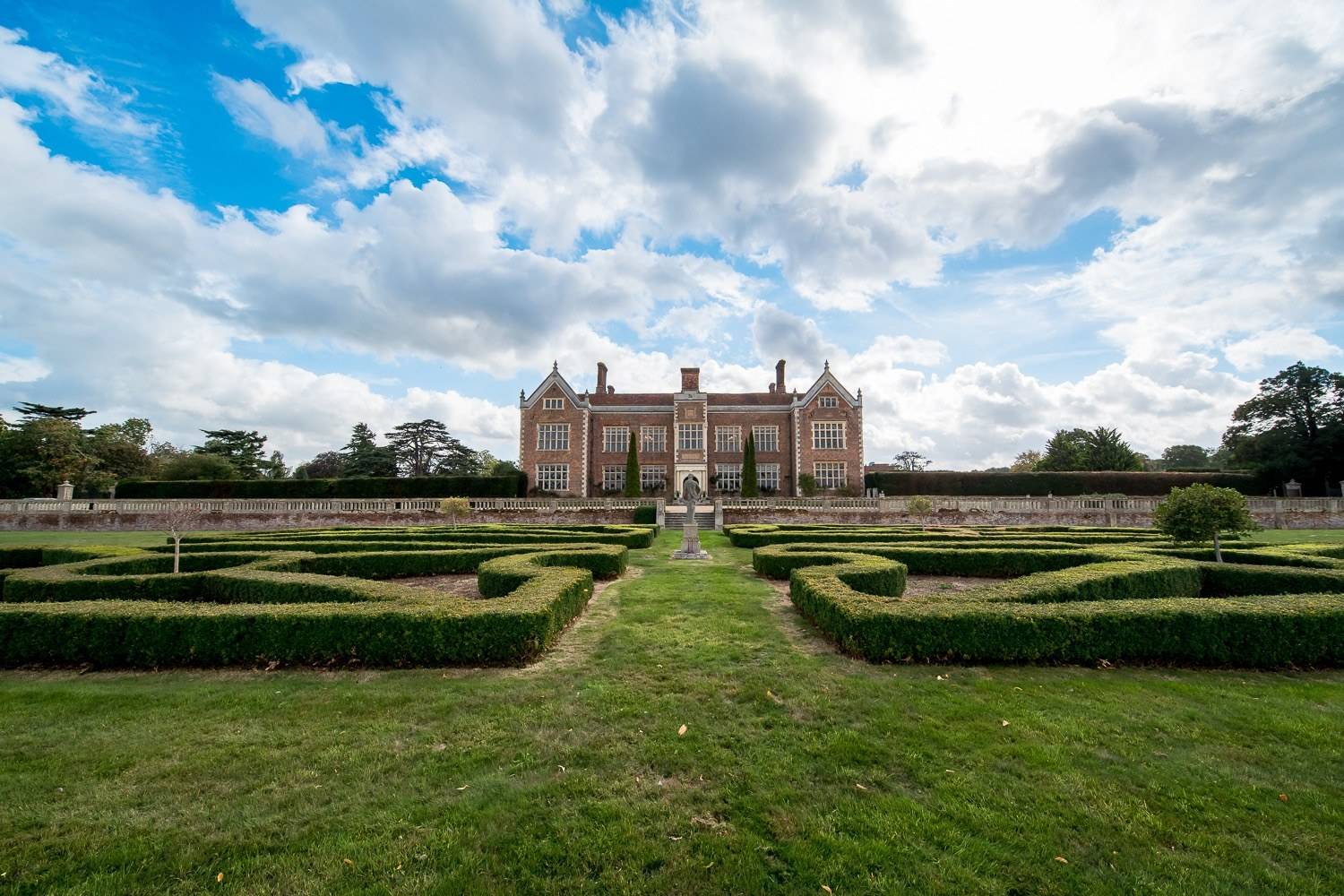 Formal parterre knot gardens and manicured box hedging framing the grand facade of North Mymms Park by Love Locations.