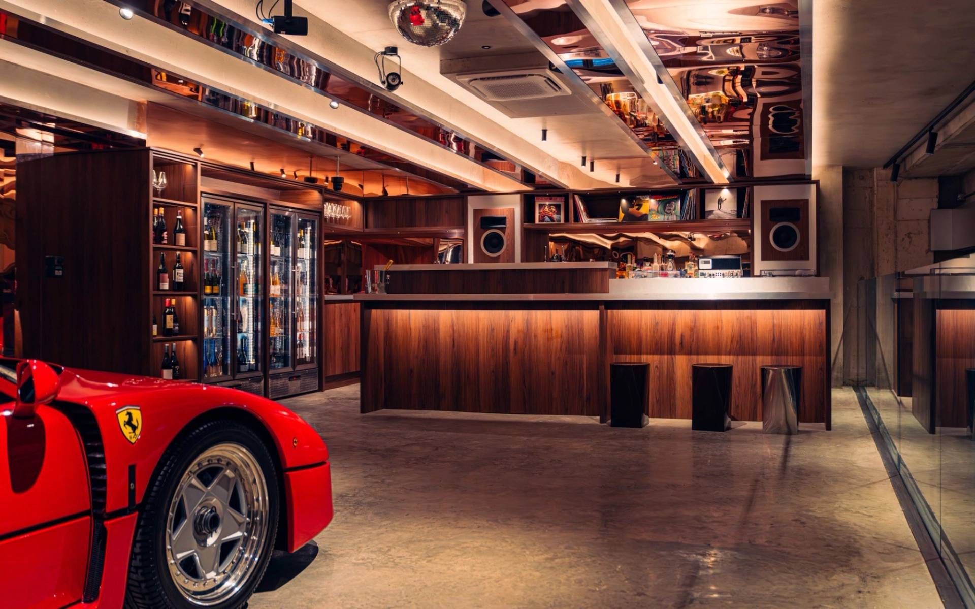 Wooden bar counter and glass beverage displays framing a red Ferrari F40 in Brentford TW8 via Love Locations.