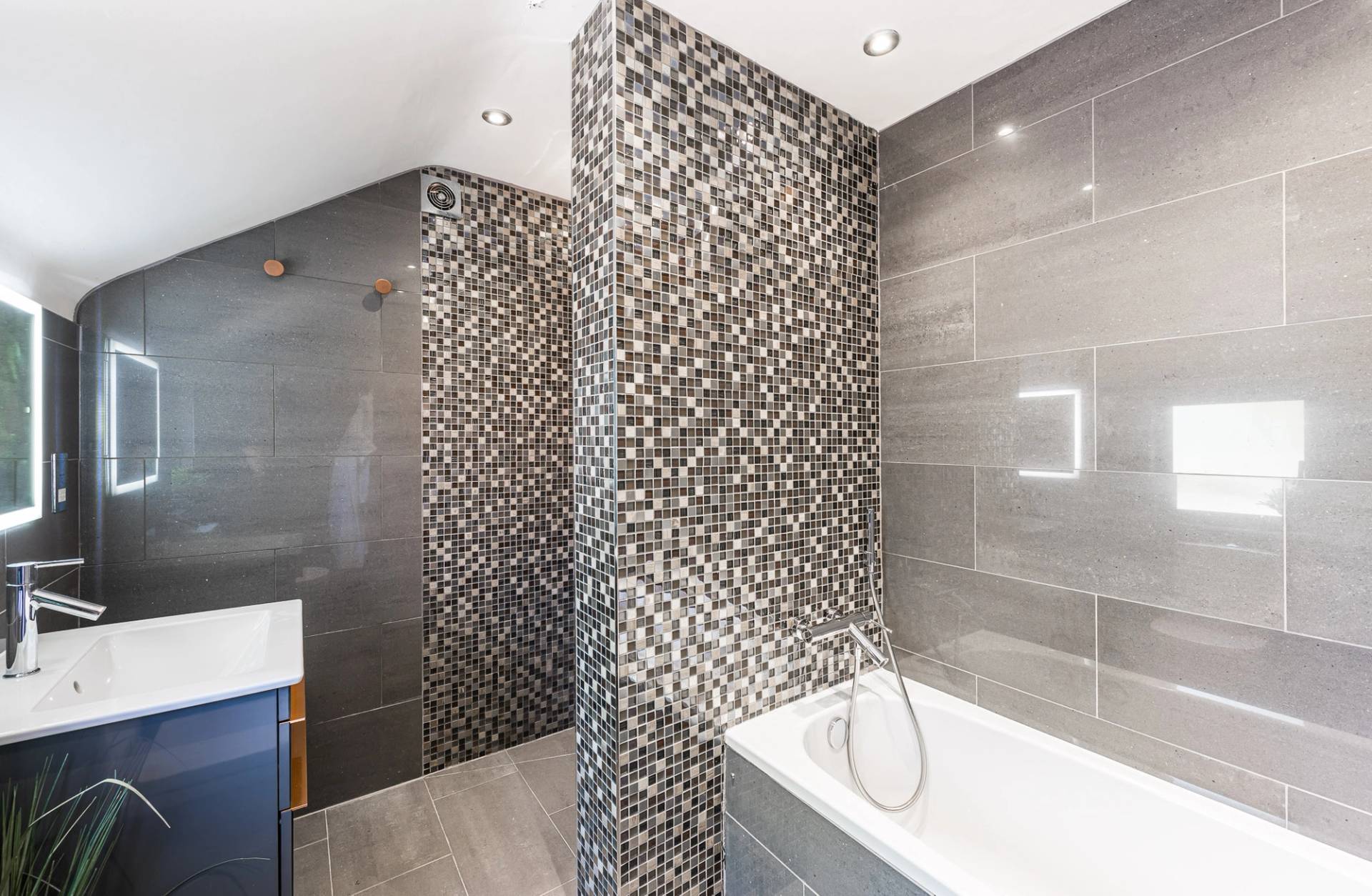 Luxury grey tiled family bathroom location with a built-in bathtub and modern square shower screen, Love Locations.