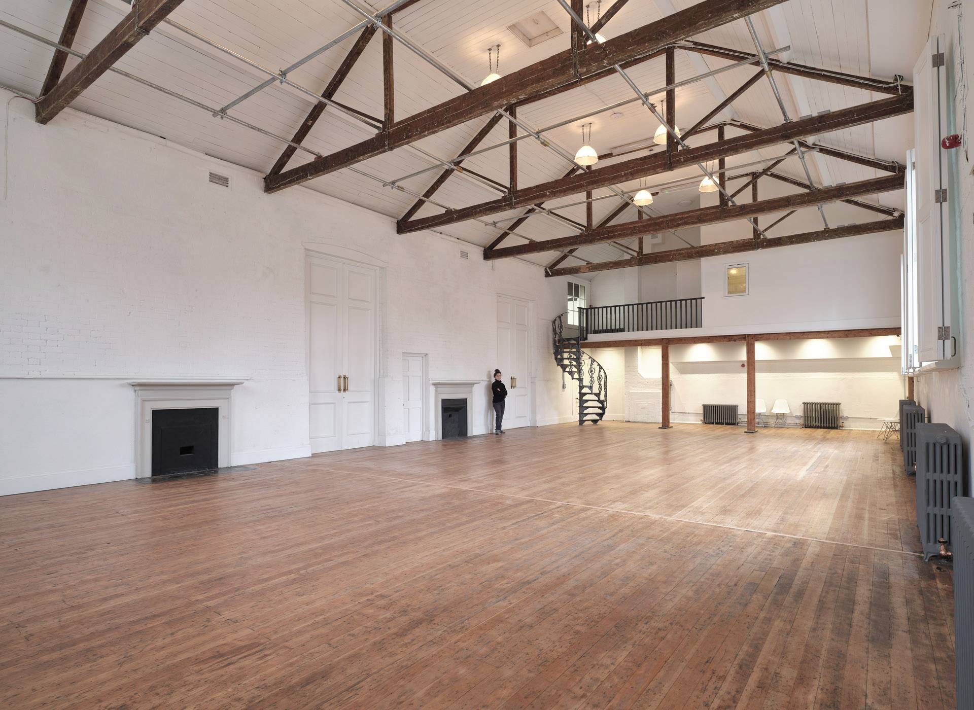 Sunlit Victorian school hall featuring exposed roof trusses, period fireplaces, and polished wood floorboards, ideal for film scene base setups, Love Locations.