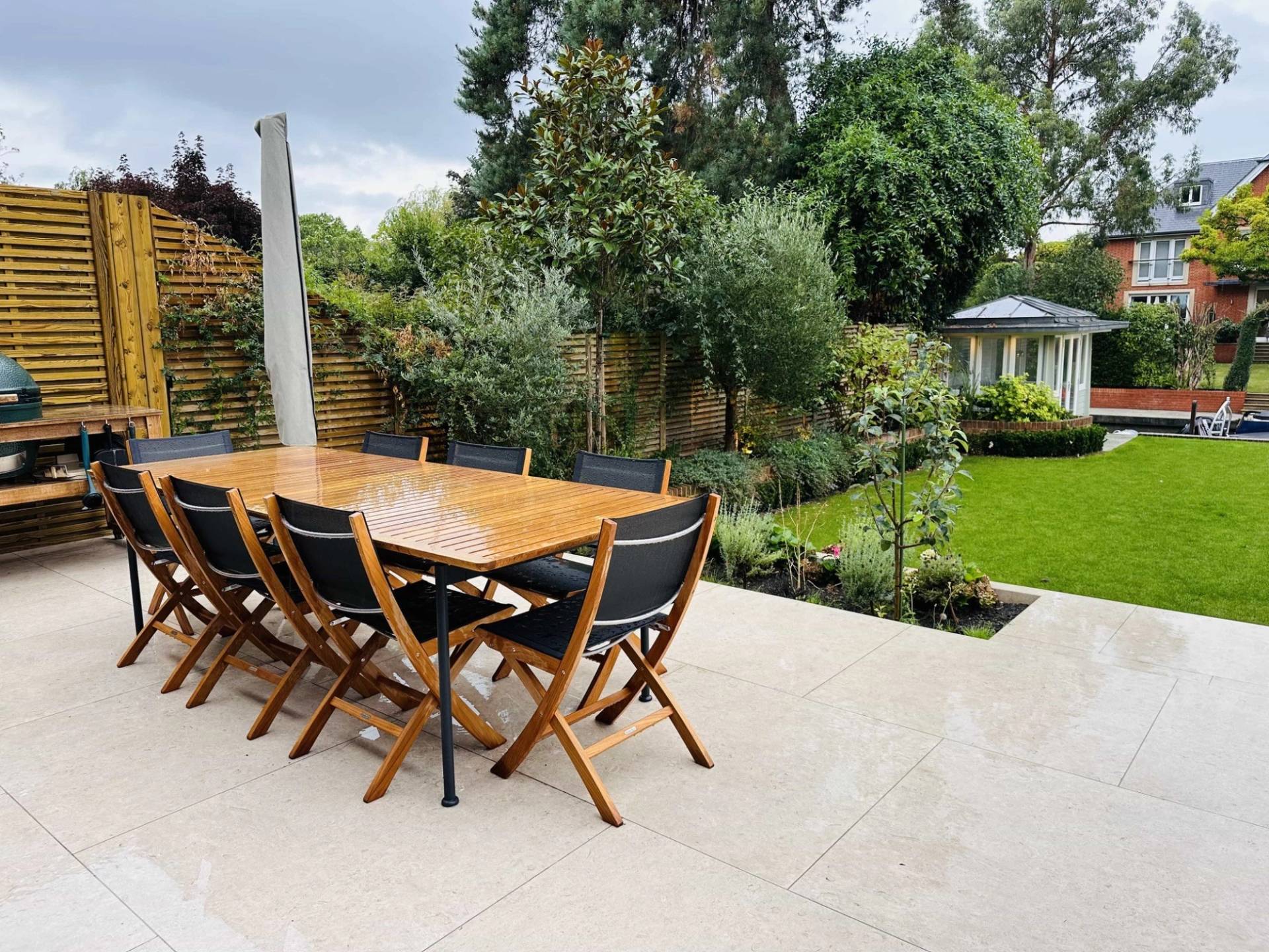 Stone outdoor patio terrace set with a wooden garden dining table and black chairs, Love Locations TW11.