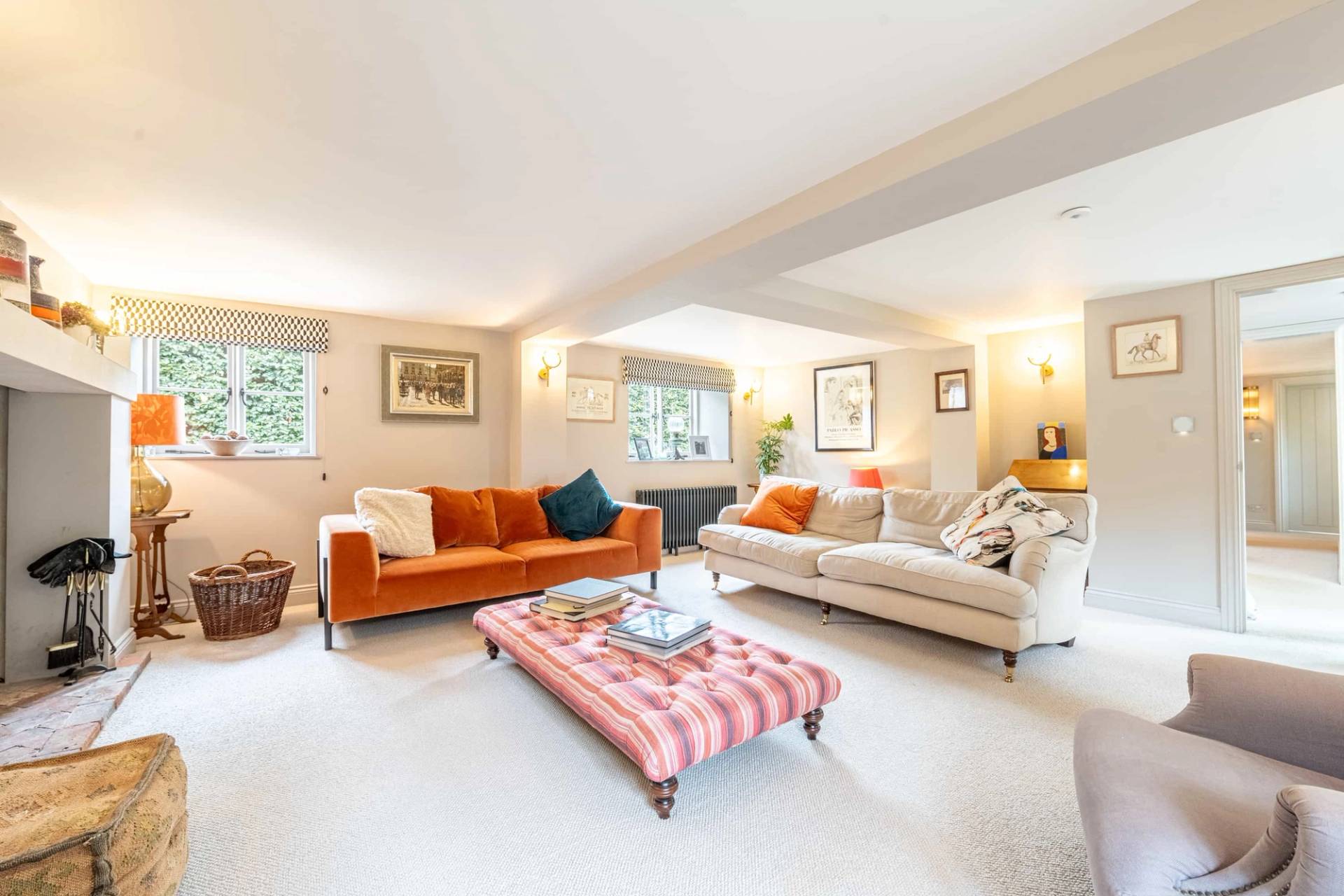Living room suite featuring an orange velvet sofa, pink striped ottoman, and twin off-white couches, Love Locations GU28.