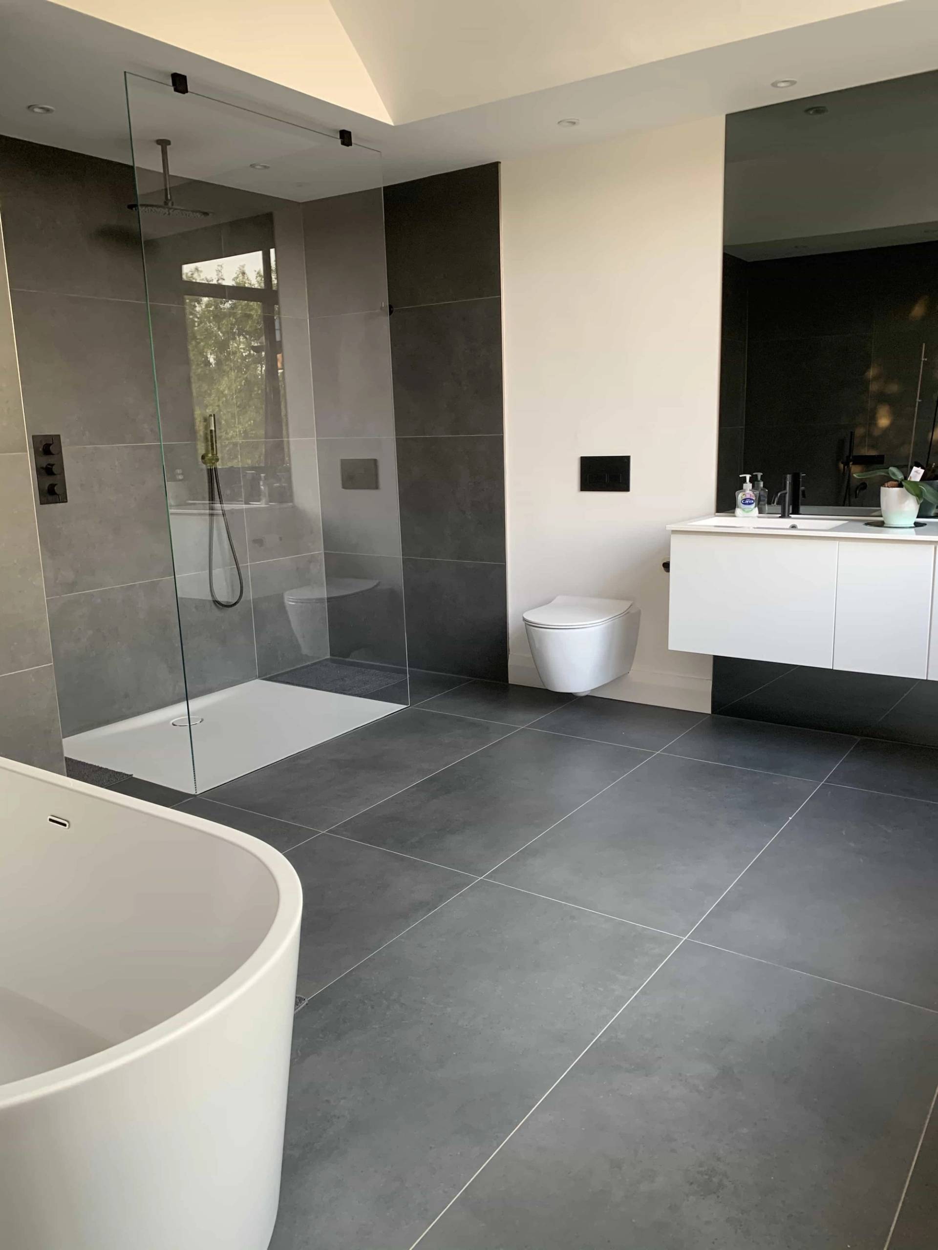 Luxury ensuite bathroom featuring a wet-room rainfall shower, freestanding tub, and dark grey slate wall tiles, perfect for skincare product shoots, Love Locations IG10.