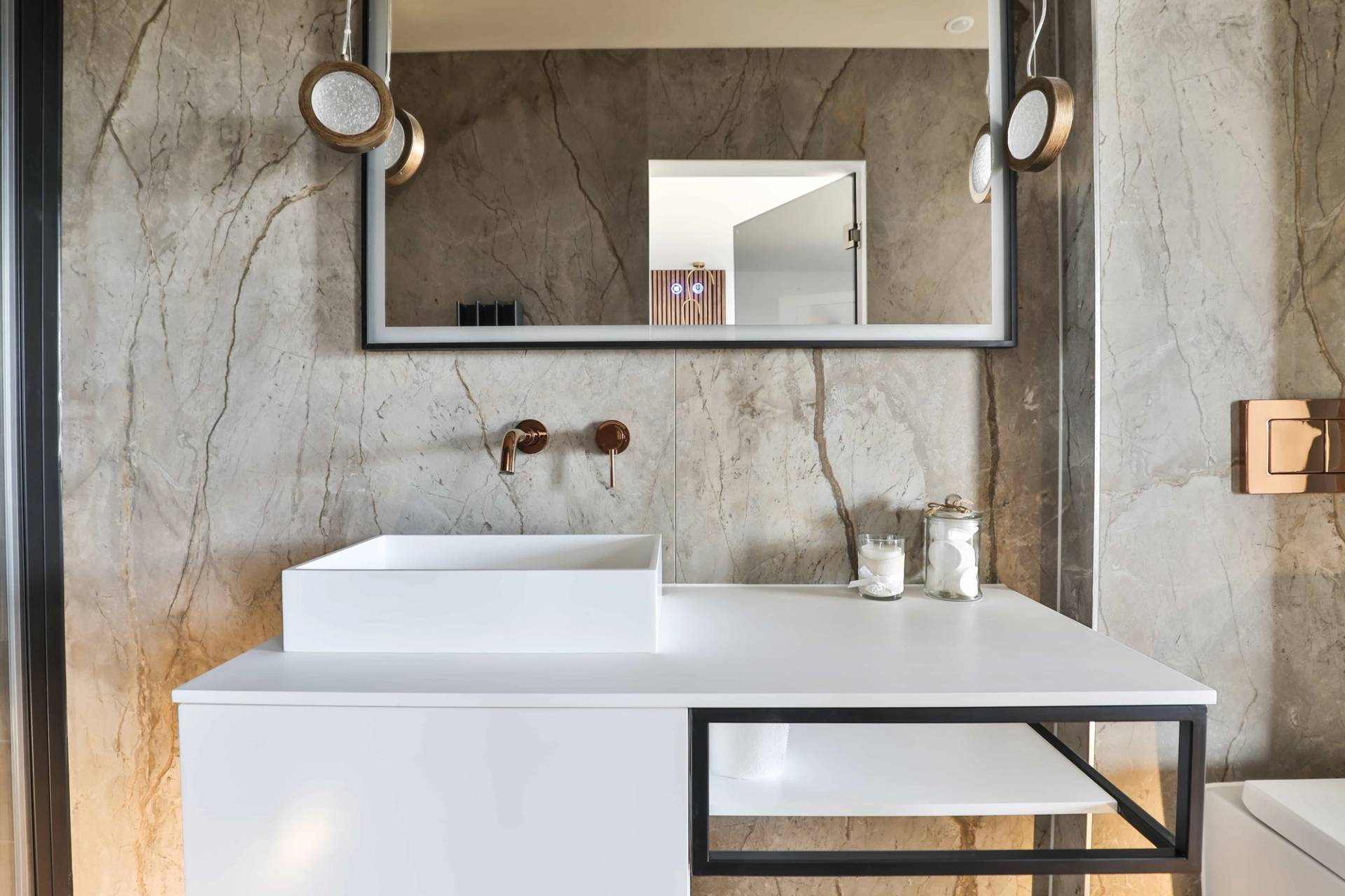 Modern bathroom vanity counter with white vessel sink, brass wall tap, and large mirror, Love Locations CV23.