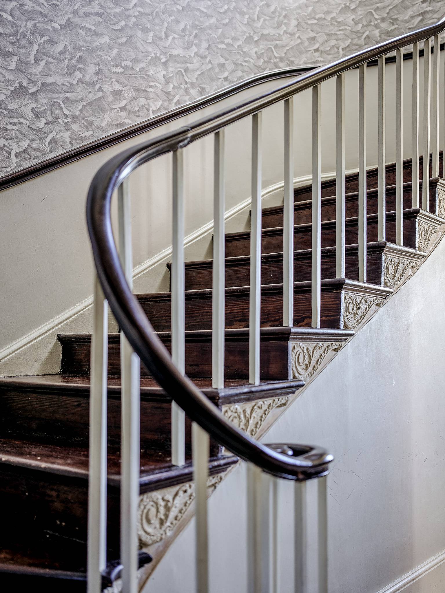 Detailed close-up of dark polished wood handrail on a white Georgian spiral staircase, Love Locations.
