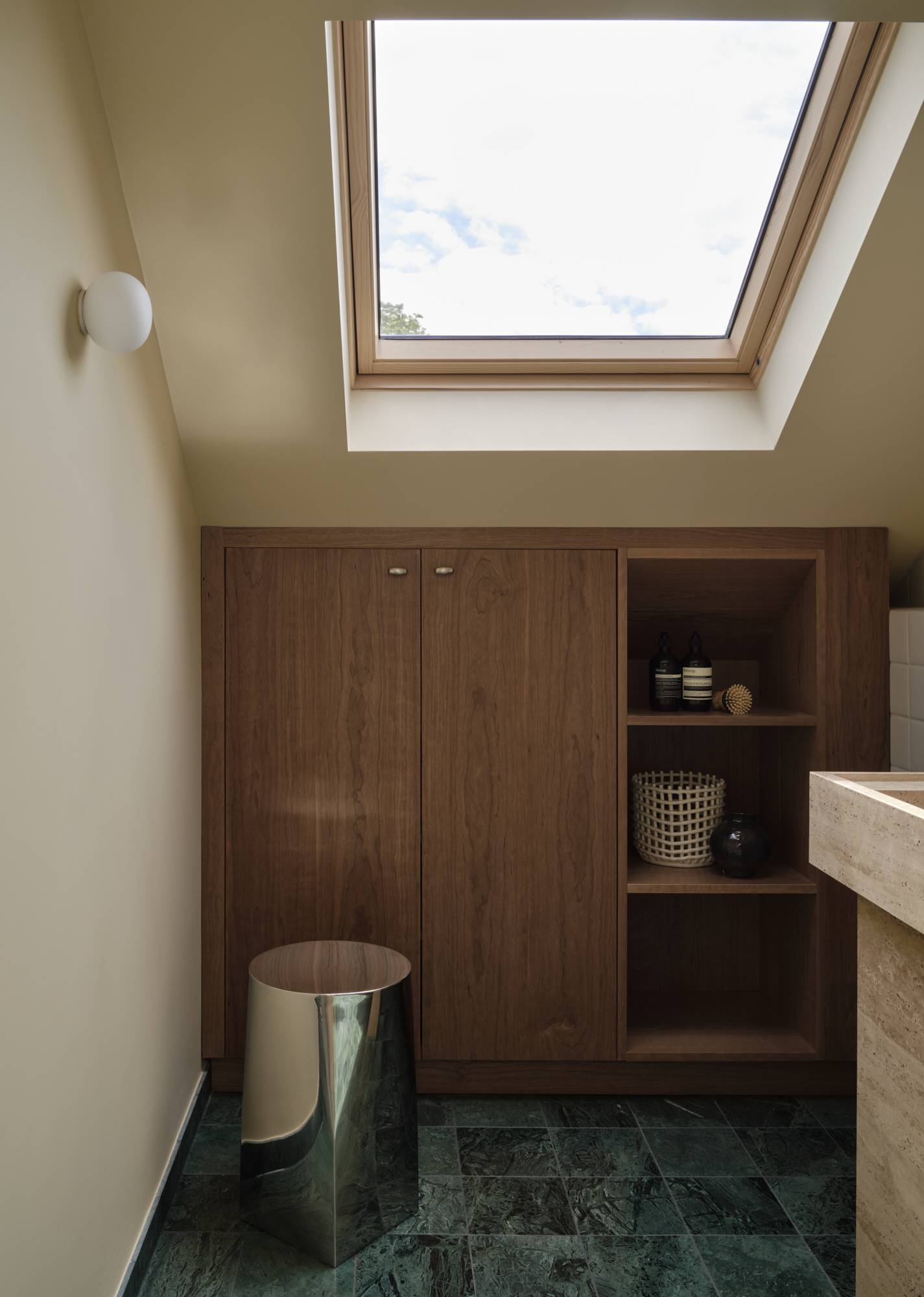 Love Locations architectural bathroom layout Lewisham SE23: Loft ensuite space emphasizing custom dark walnut storage closets beneath a sloped ceiling skylight.
