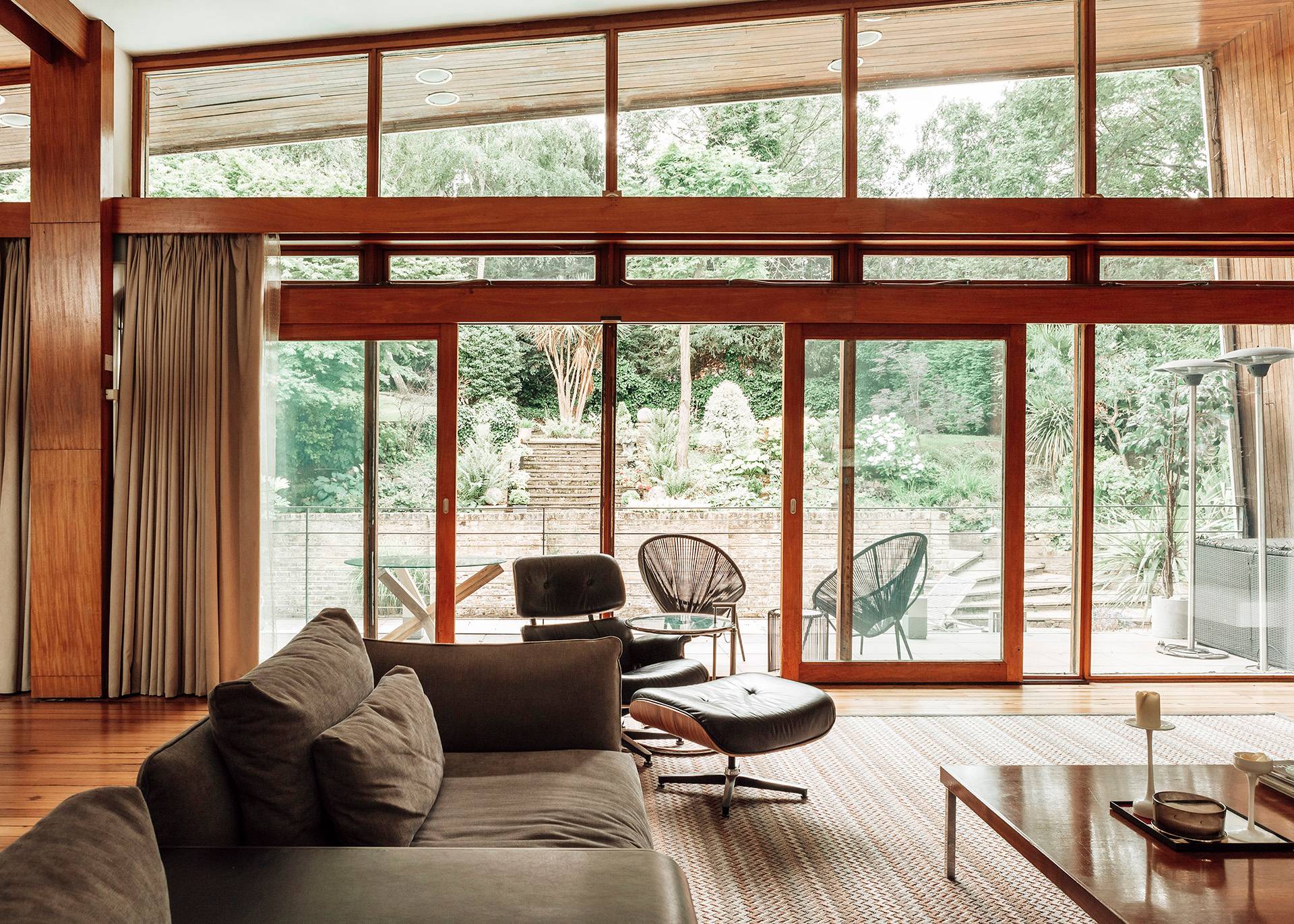 Bright mid-century living room featuring natural wood window frames bathing the interior in soft daylight, ideal for lifestyle brand filming, Love Locations BR1.