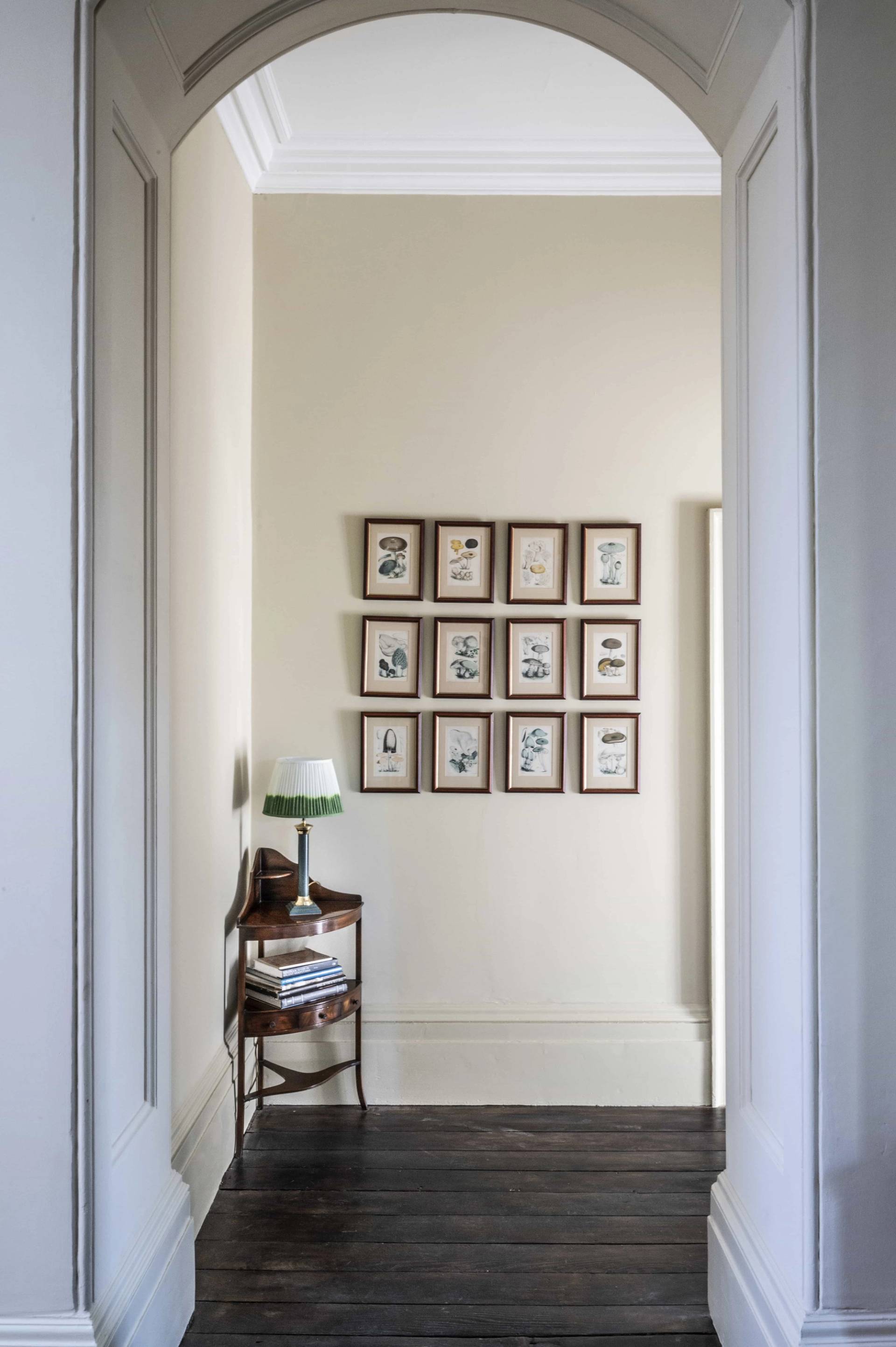Symmetrical gallery wall display of framed botanical prints in a neutral hallway transition, Love Locations.