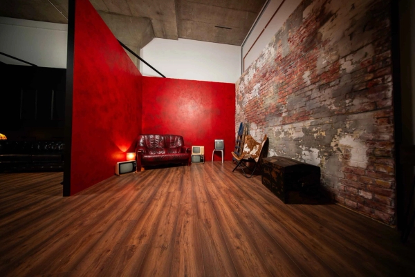 Wide perspective of a red textured studio set alongside a distressed exposed brick wall, Love Locations N15.