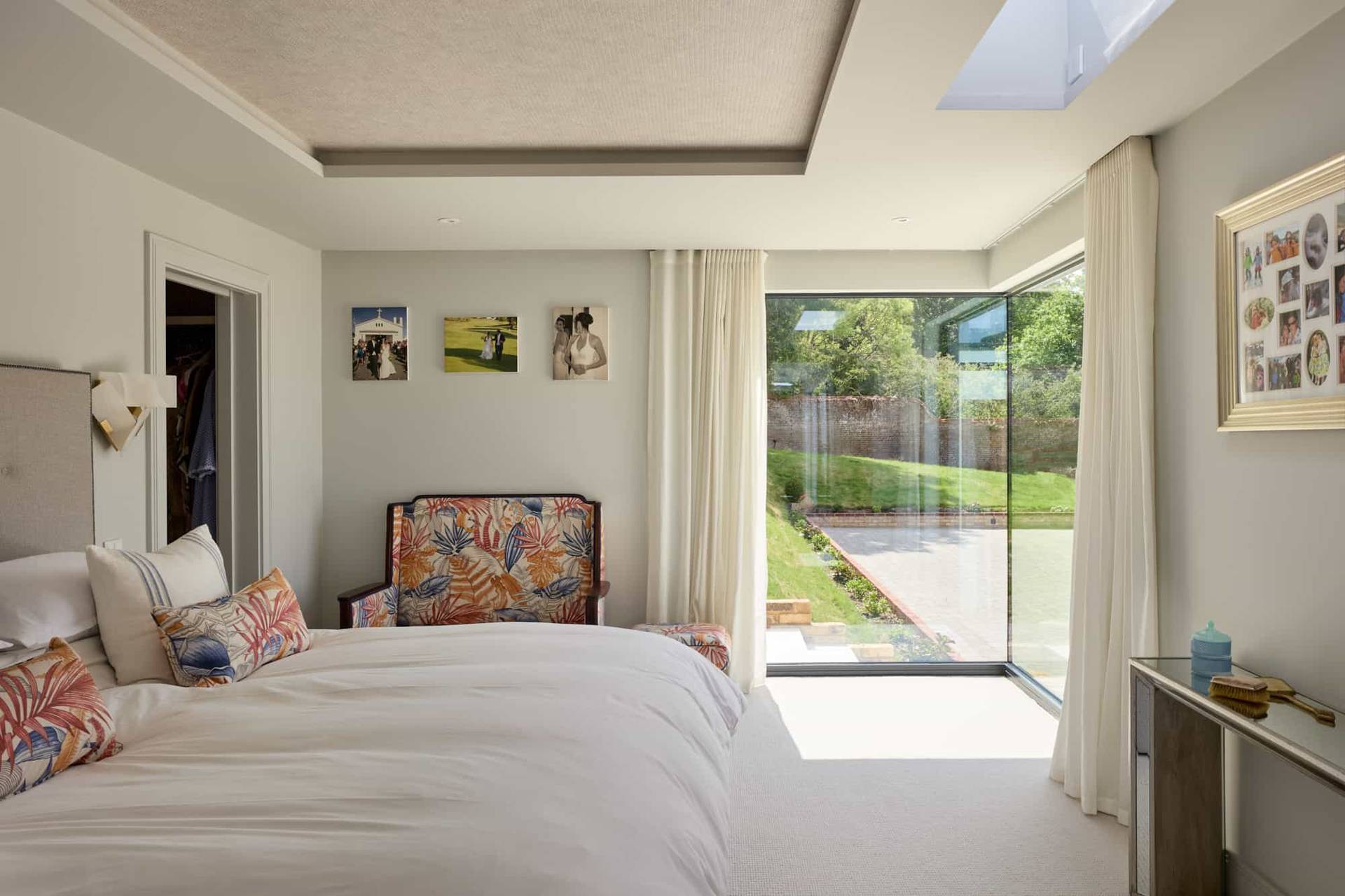 Bright master bedroom with large glass sliding doors framing landscaped garden views, ideal for luxury interior features, Love Locations.