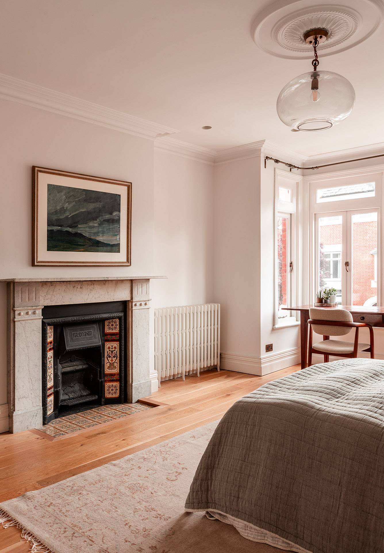 Bedside view of a light-filled bedroom with classic cast iron radiator and neutral interior styling, Love Locations TW1.